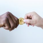 close up shot of two people holding a gold coin